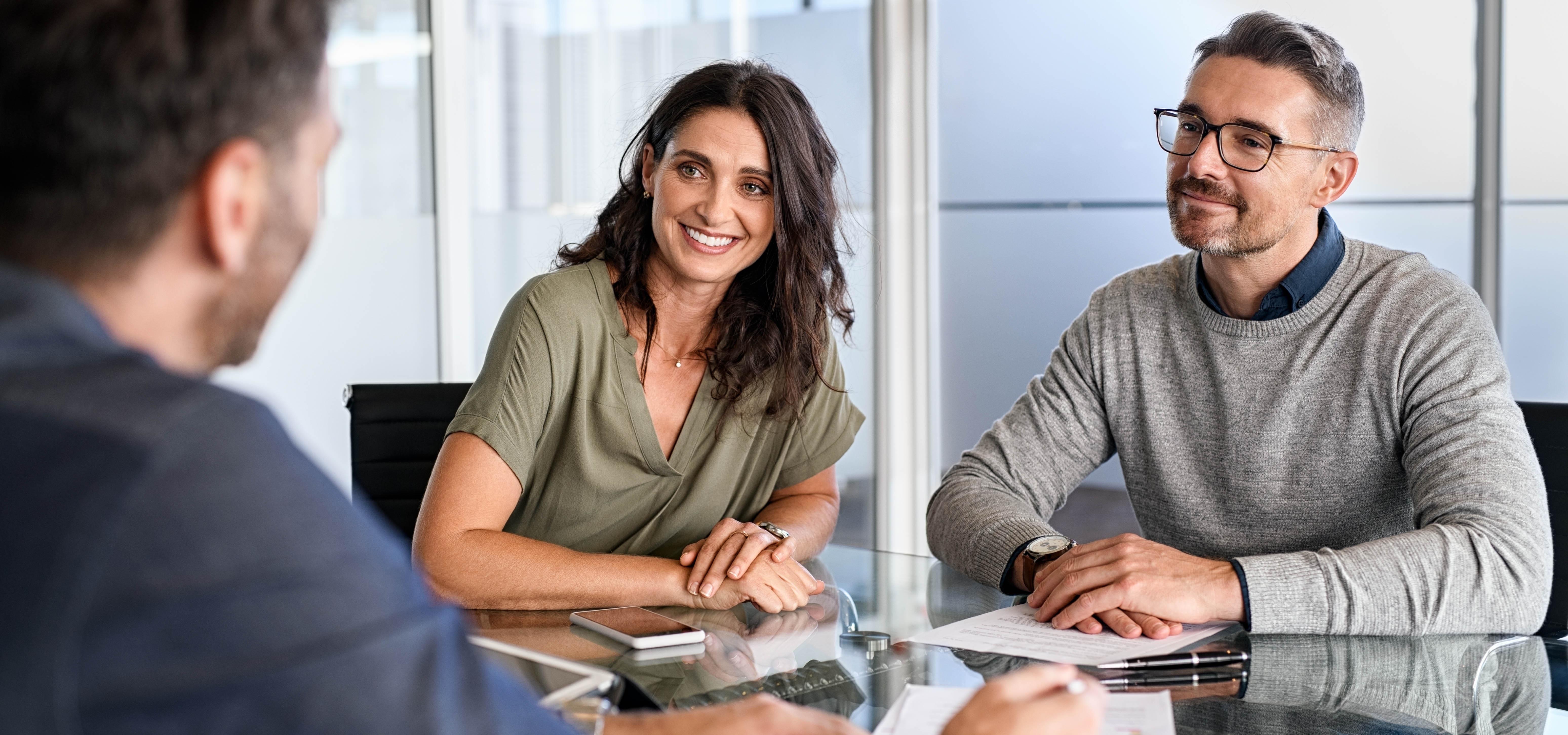 Smiling mature couple meeting with bank manager for investment. Mid adult woman with husband listening to businessman during meeting in conference room. Middle aged couple meeting loan advisor.